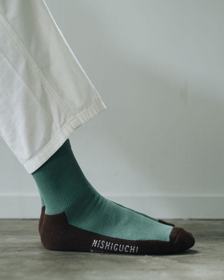 Cotton Cashmere Walk Socks – Kusamochi by Nishiguchi Kutsushita: ankle socks with green uppers and dark brown heels, toes, and soles. Available in men's sizes—see our size chart for the perfect fit. Displayed on a plain gray background.