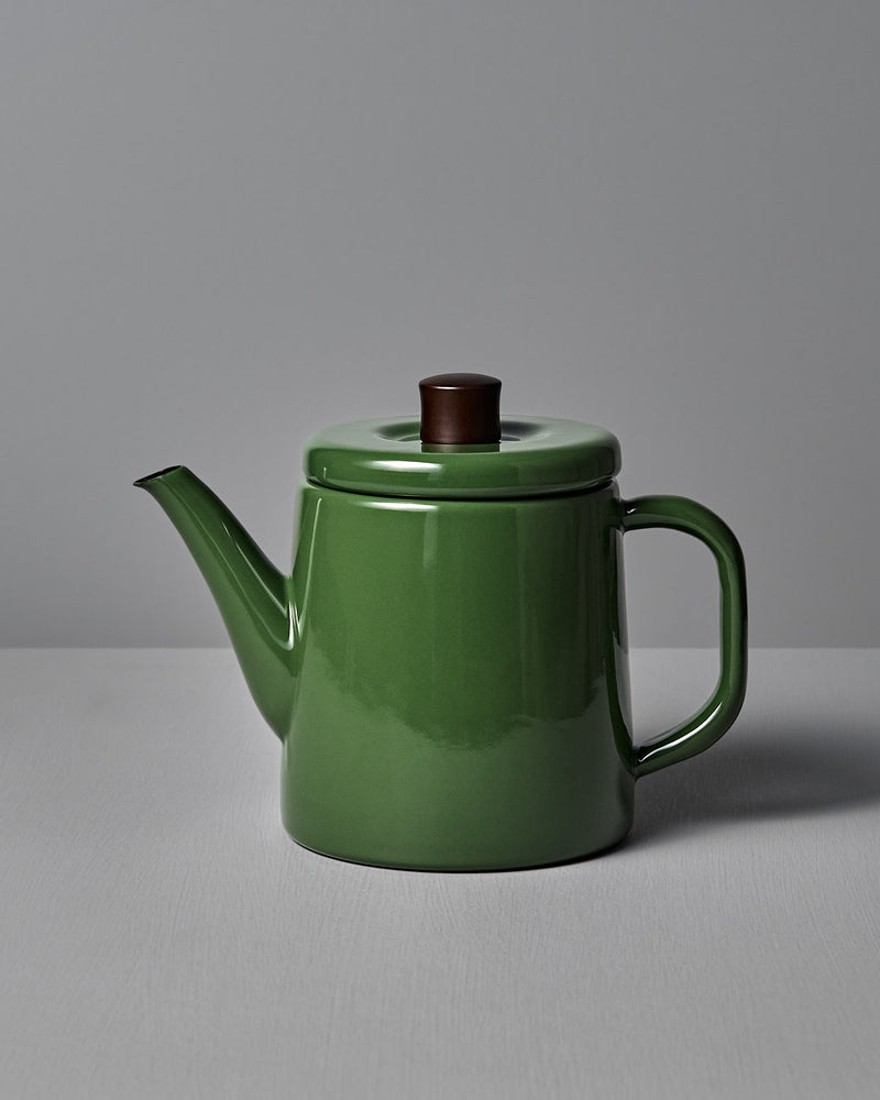 A Noda Horo Potoru Stove-top Kettle/Teapot in green, featuring a brown wooden lid handle and inspired by traditional Japanese design, is set against a gray background on a plain surface.