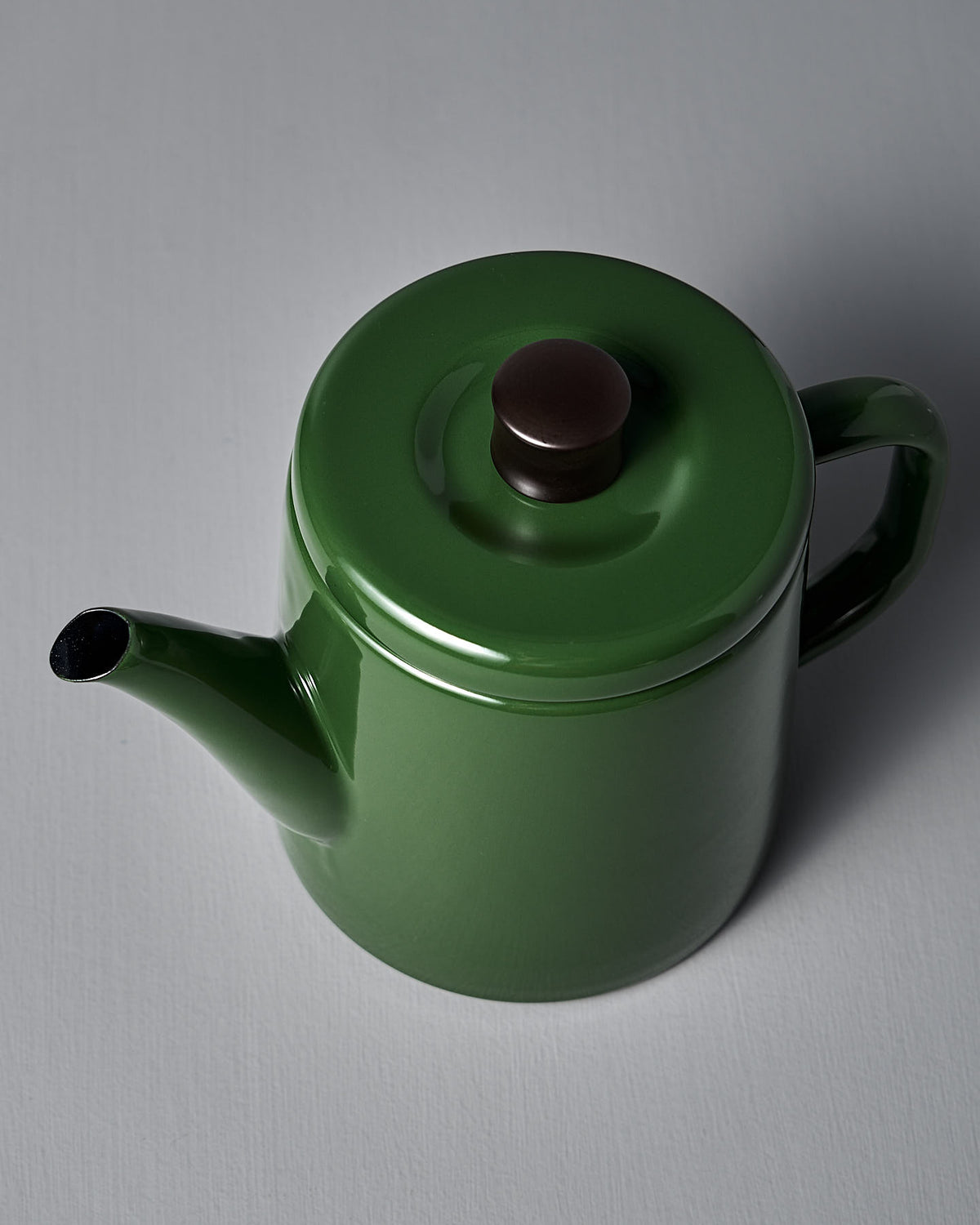 The Noda Horo Potoru Stove-top Kettle/Teapot in green, with a brown lid knob, elegantly rests on a light gray surface.