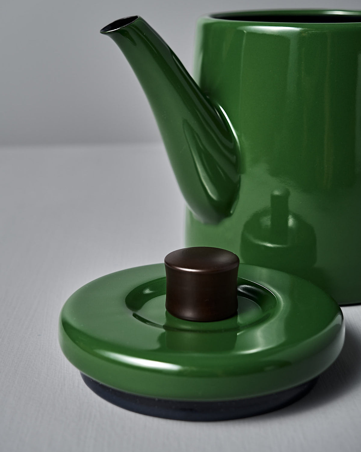 The Noda Horo Potoru Stove-top Kettle/Teapot in green, featuring a brown knob lid, rests gracefully on a light gray background, evoking the elegance of traditional Japanese design.