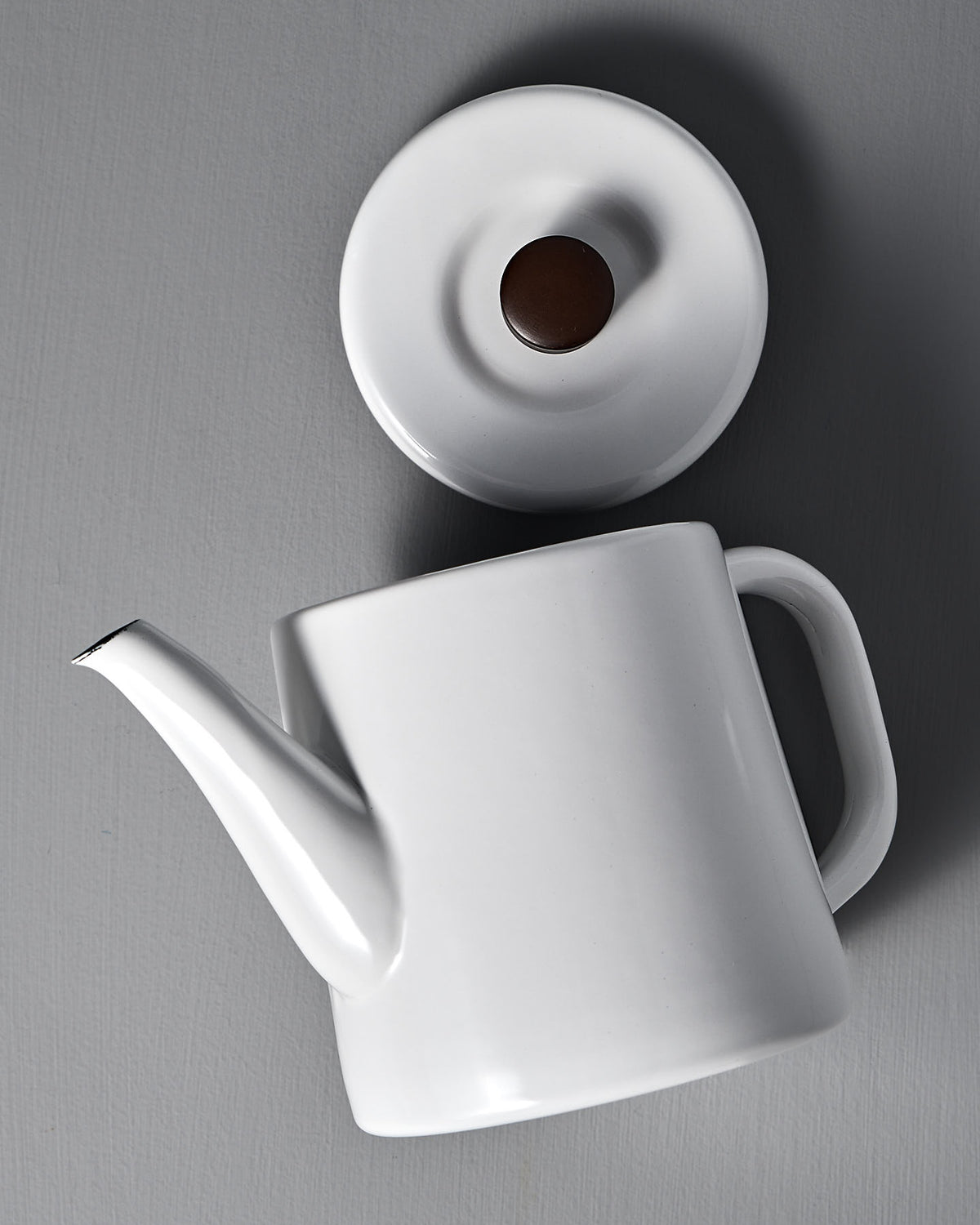 The Potoru Stove-top Kettle/Teapot in white by Noda Horo, evocative of traditional Japanese kitchenware, sits with its lid detached on a gray surface.