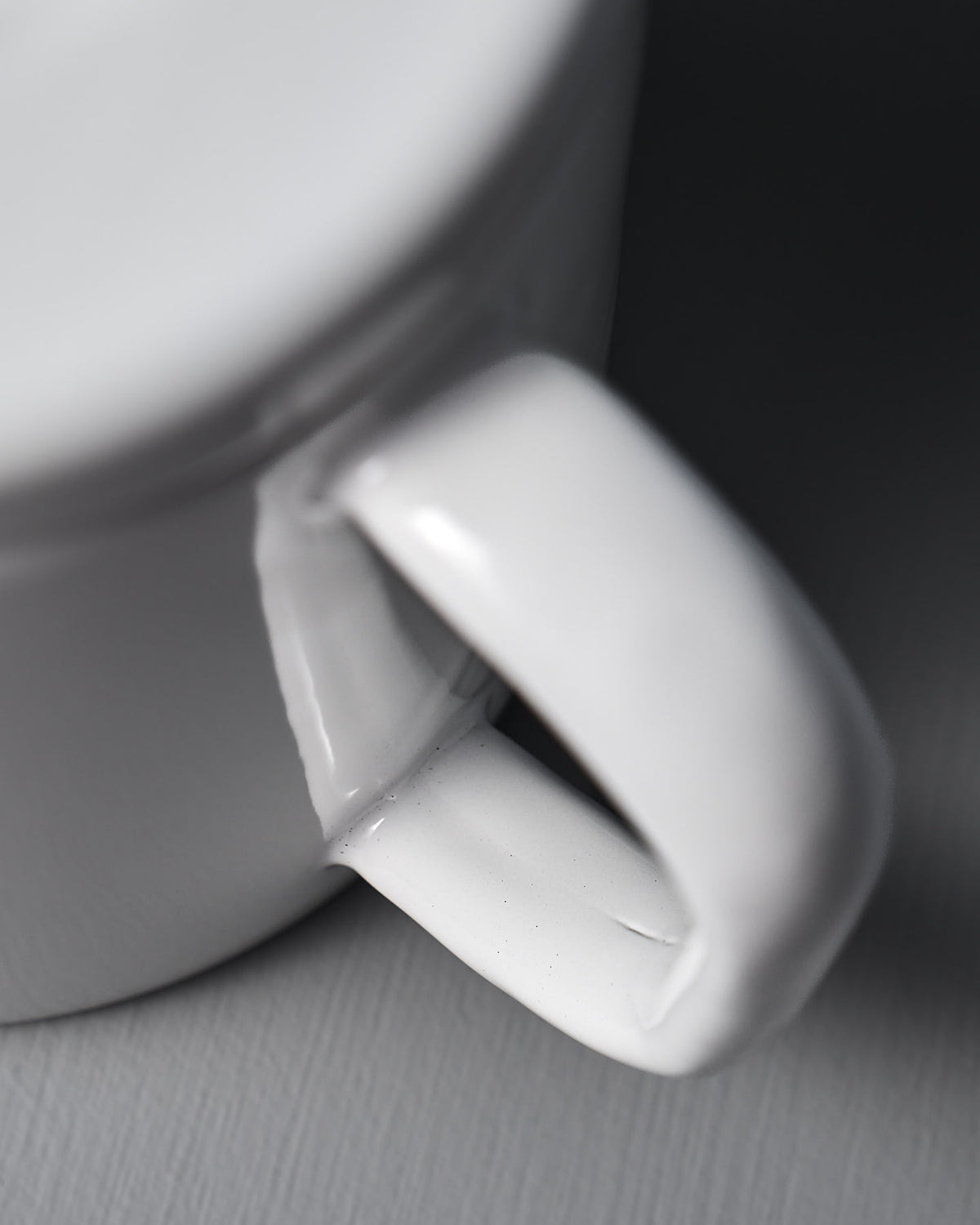 Close-up of the handle and side of a Noda Horo Potoru Stove-top Kettle/Teapot – White on a gray surface, evocative of elegant Japanese kitchenware.