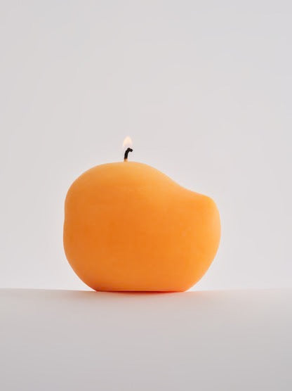 A handmade Nonna&#39;s Grocer mango candle, made with a soy wax blend, sitting on a white surface.