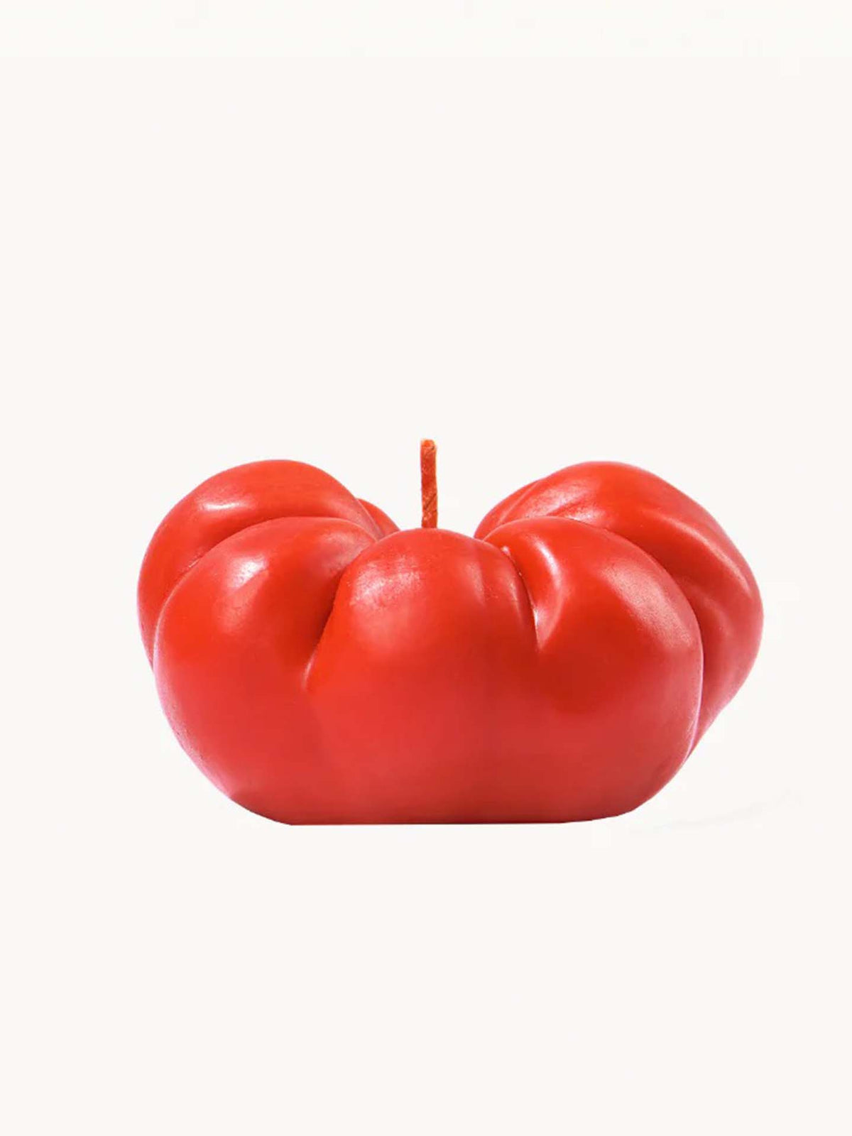 The Scented Tomato Candle from Nonna&#39;s Grocer is a hand-finished piece crafted from a soy wax blend, showcasing a vivid red hue with a wick on top, all presented against a plain white background.