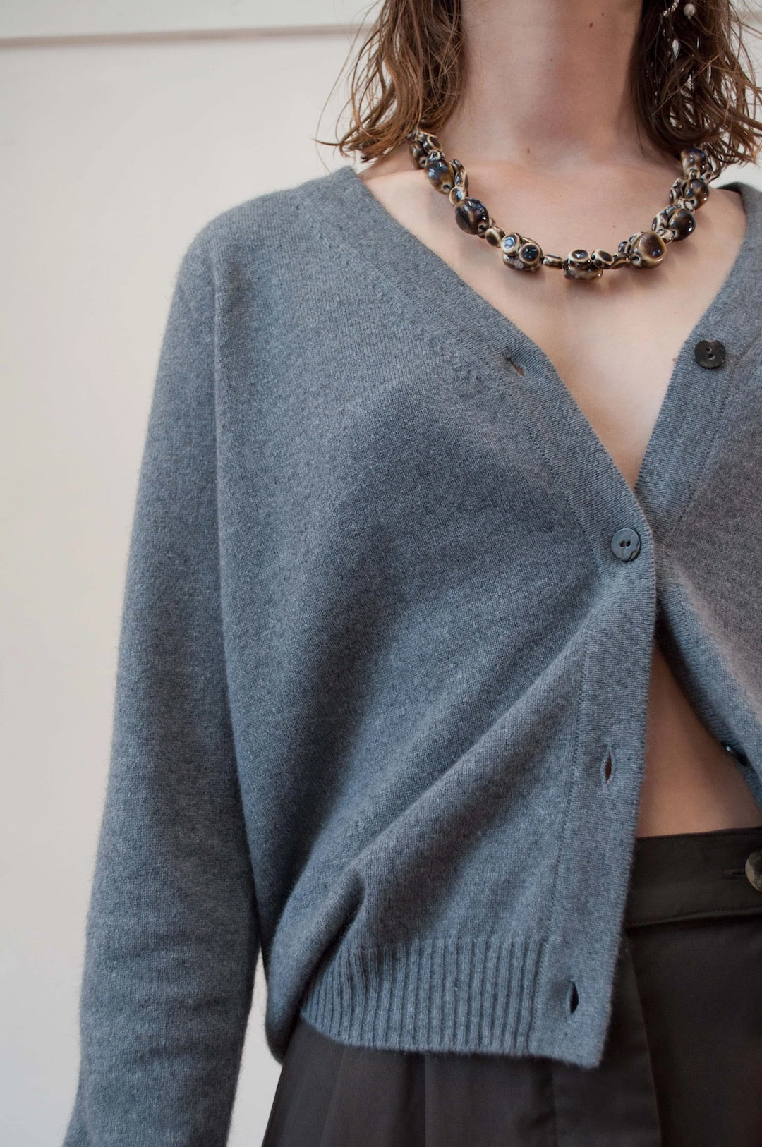 A woman wearing a Kom Cardigan – Stone by OVNA OVICH and necklace.