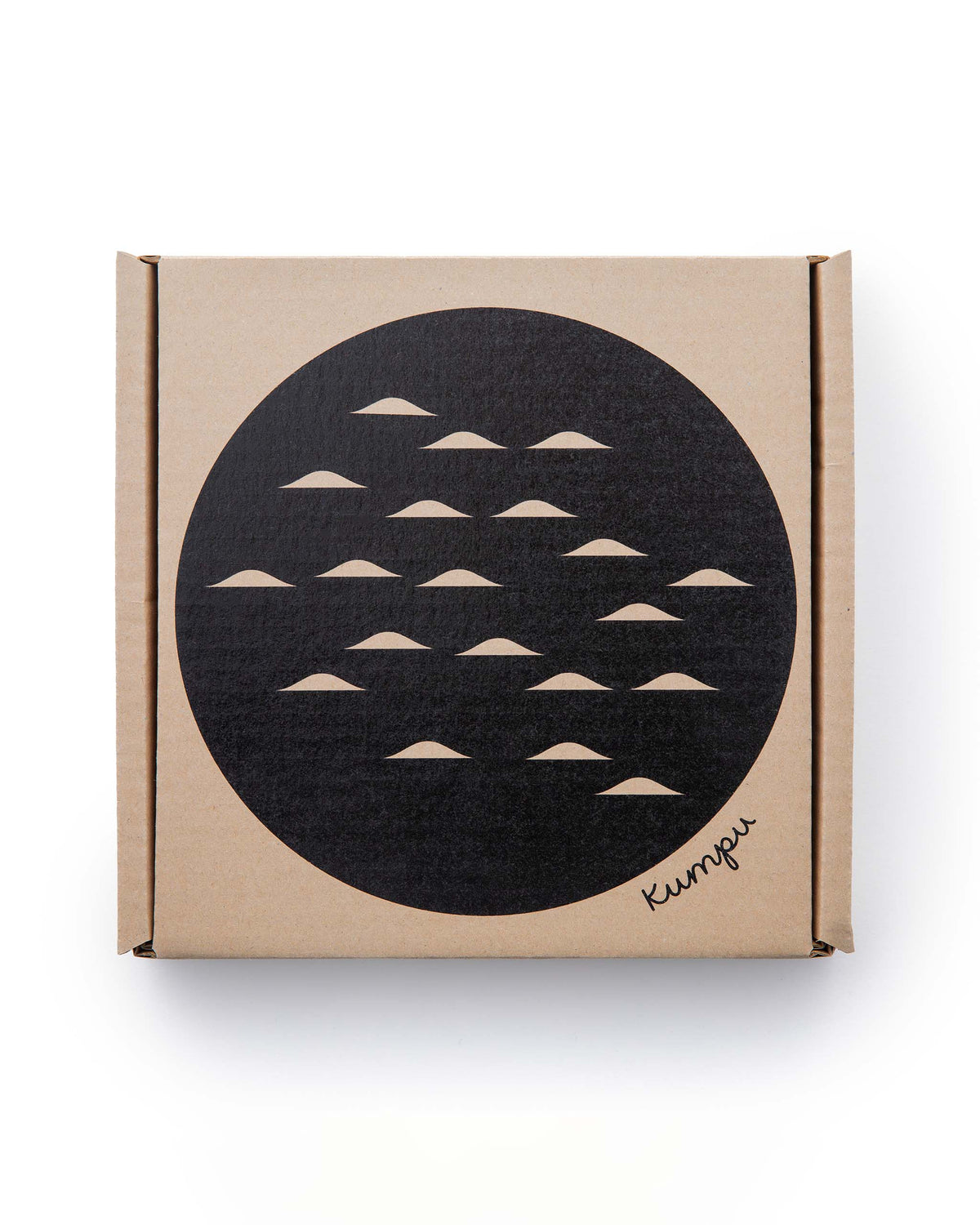 Square cardboard box featuring a black circle with small crescent patterns and the text “Kumpu” in the corner.