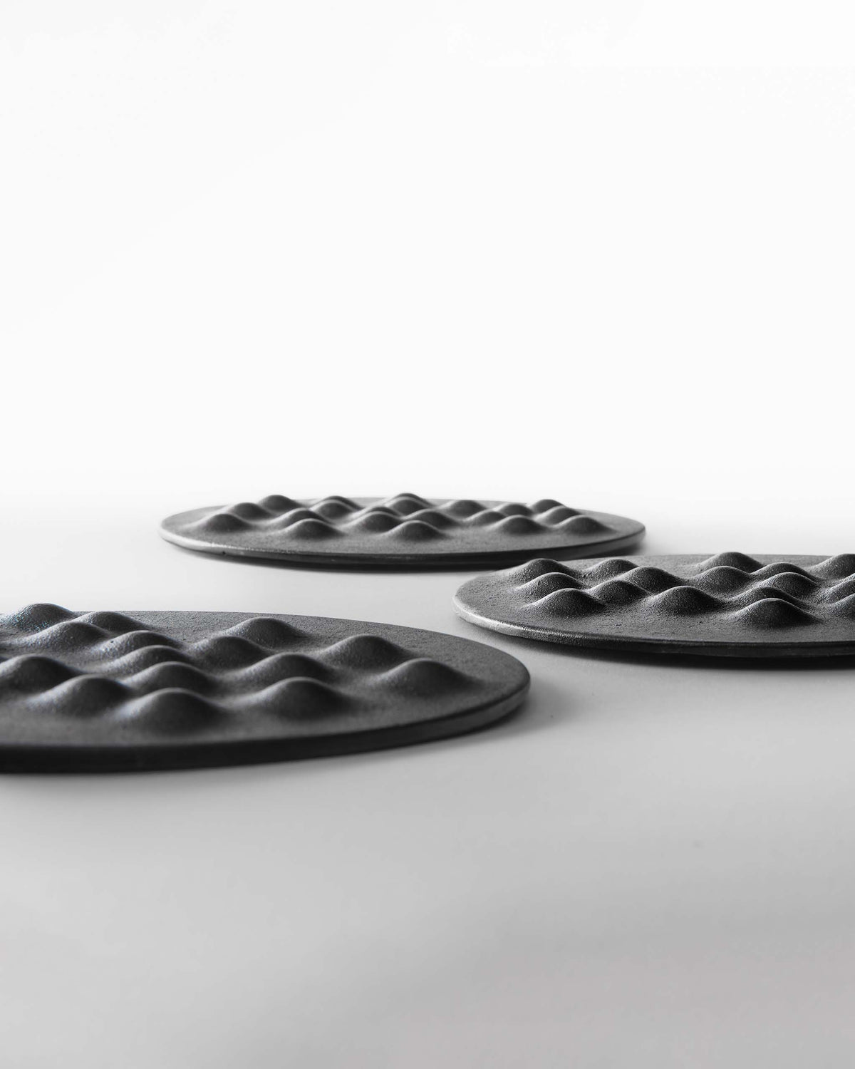 Three circular cast iron plates featuring a raised, dimpled texture.