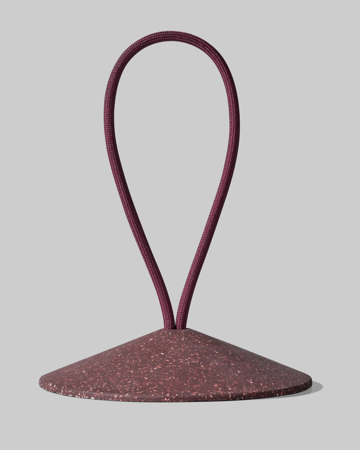 A maroon looped cord is attached to the top of a speckled, cone-shaped base against a light gray background.