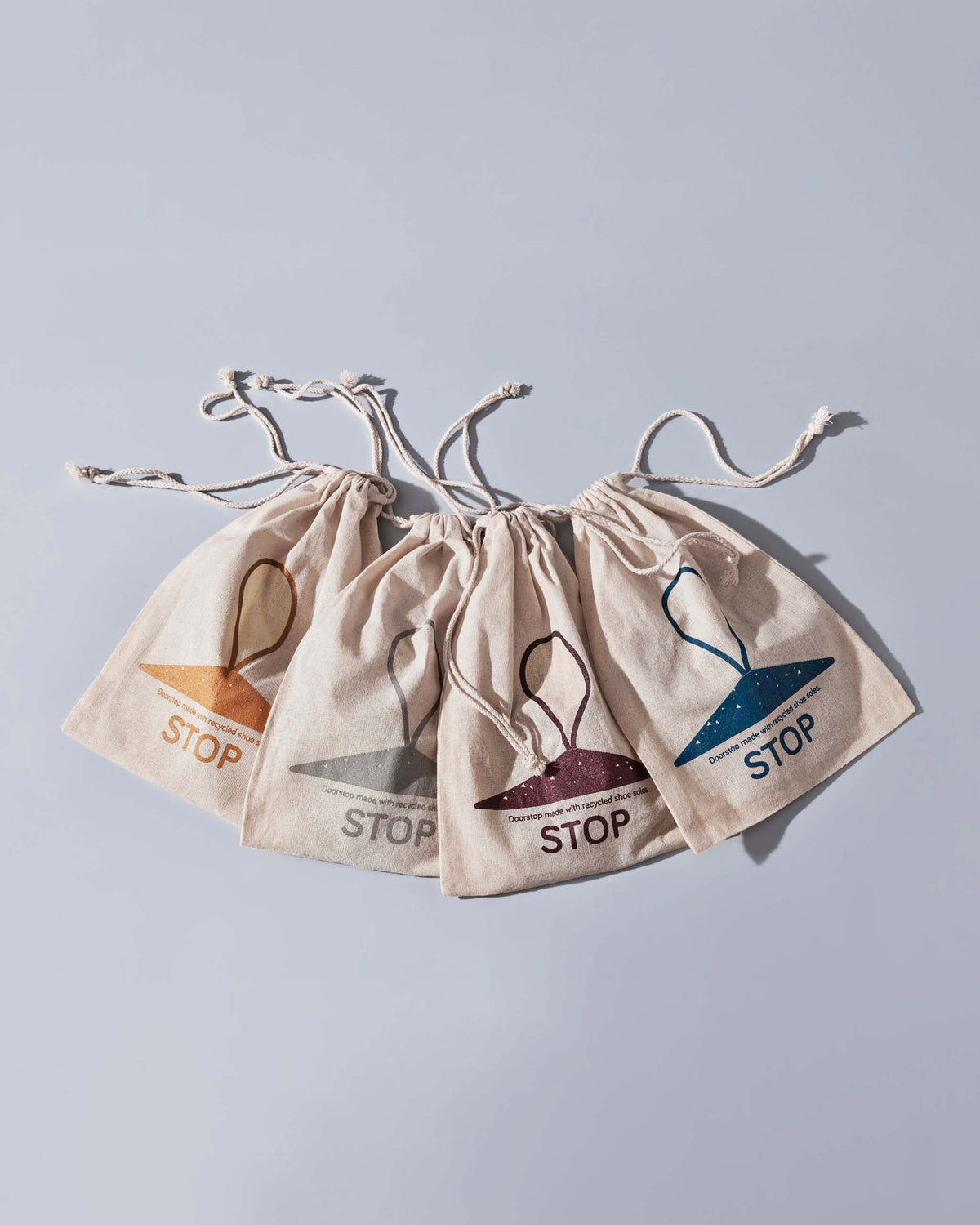 Four drawstring fabric bags with printed top graphics and the word “STOP” in different colors, arranged side by side on a light background.