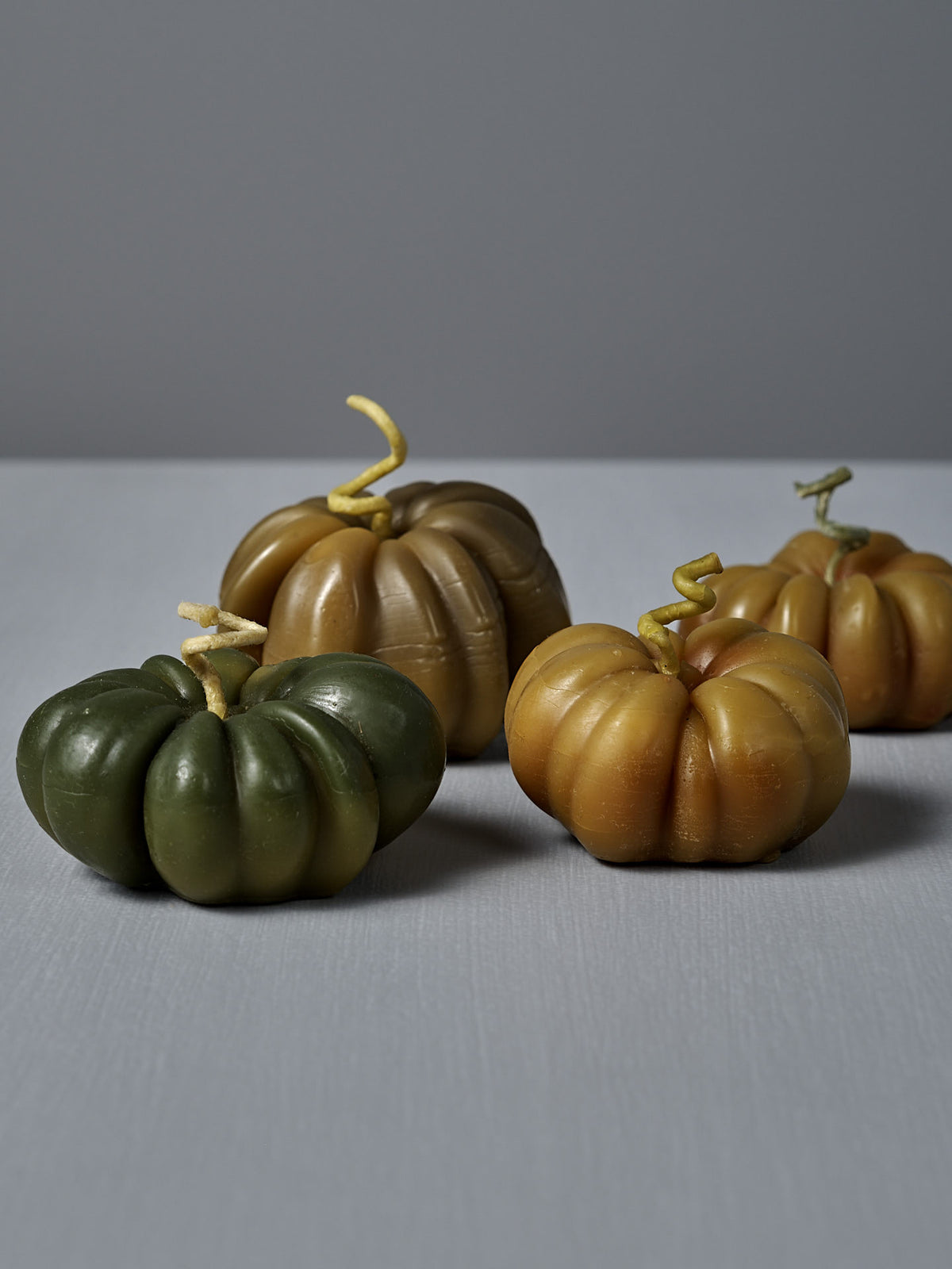 A small Green Heirloom Tomato Candle, crafted from natural beeswax in New Zealand, sits on a light gray surface against a plain gray background.