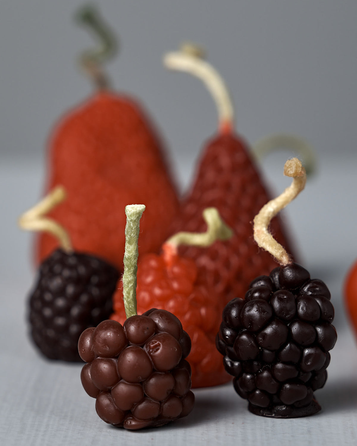Mixed Berries Candles – Box of 12: Delightful candles shaped like berries and pears with textured surfaces and playful stems, arranged on a neutral background—ideal for pairing with beeswax fruit candles as unique birthday cake decorations, inspired by the vibrant colors of New Zealand beeswax.