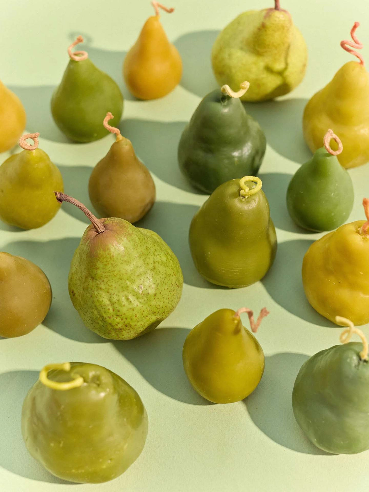 A large handmade Green Pear Candle is displayed on a light green surface.