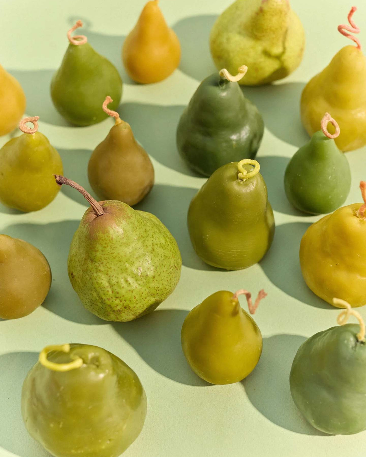 A large handmade Green Pear Candle is displayed on a light green surface.