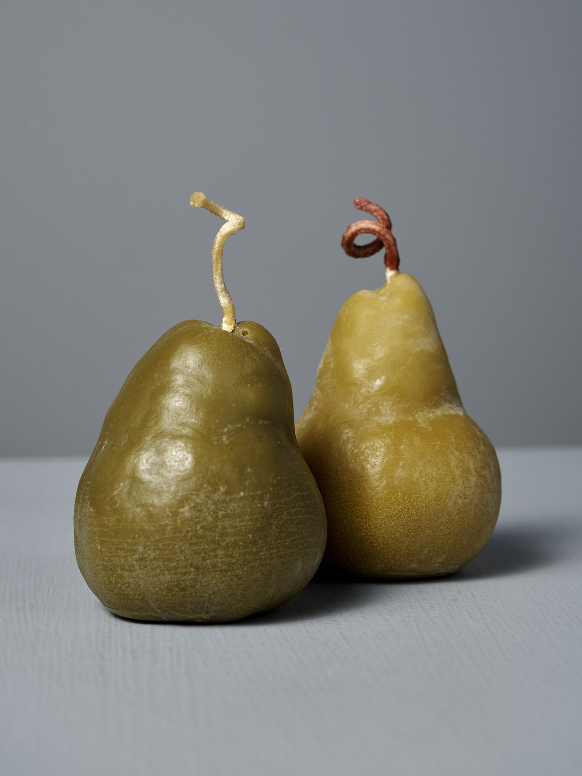 A large handmade Green Pear Candle with a textured surface and visible wick sits on a light gray surface against a gray background.