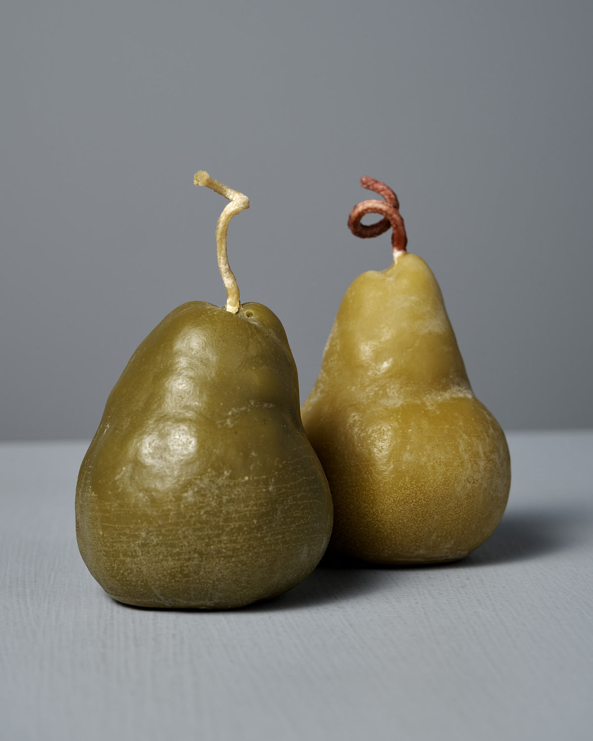 A large handmade Green Pear Candle with a textured surface and visible wick sits on a light gray surface against a gray background.