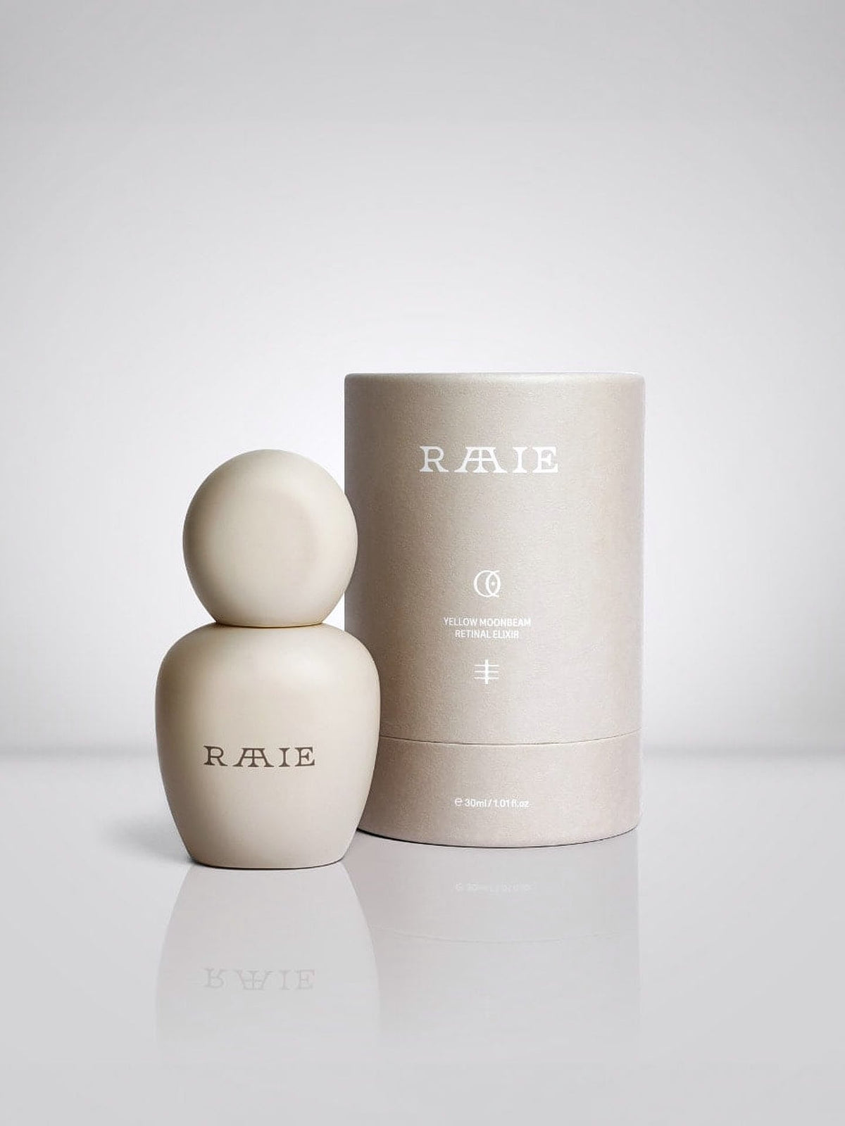 A minimalist-designed white perfume bottle labeled &quot;Yellow Moonbeam Retinal Elixir,&quot; featuring a hint of niacinamide in its formulation, is placed next to its cylindrical packaging.