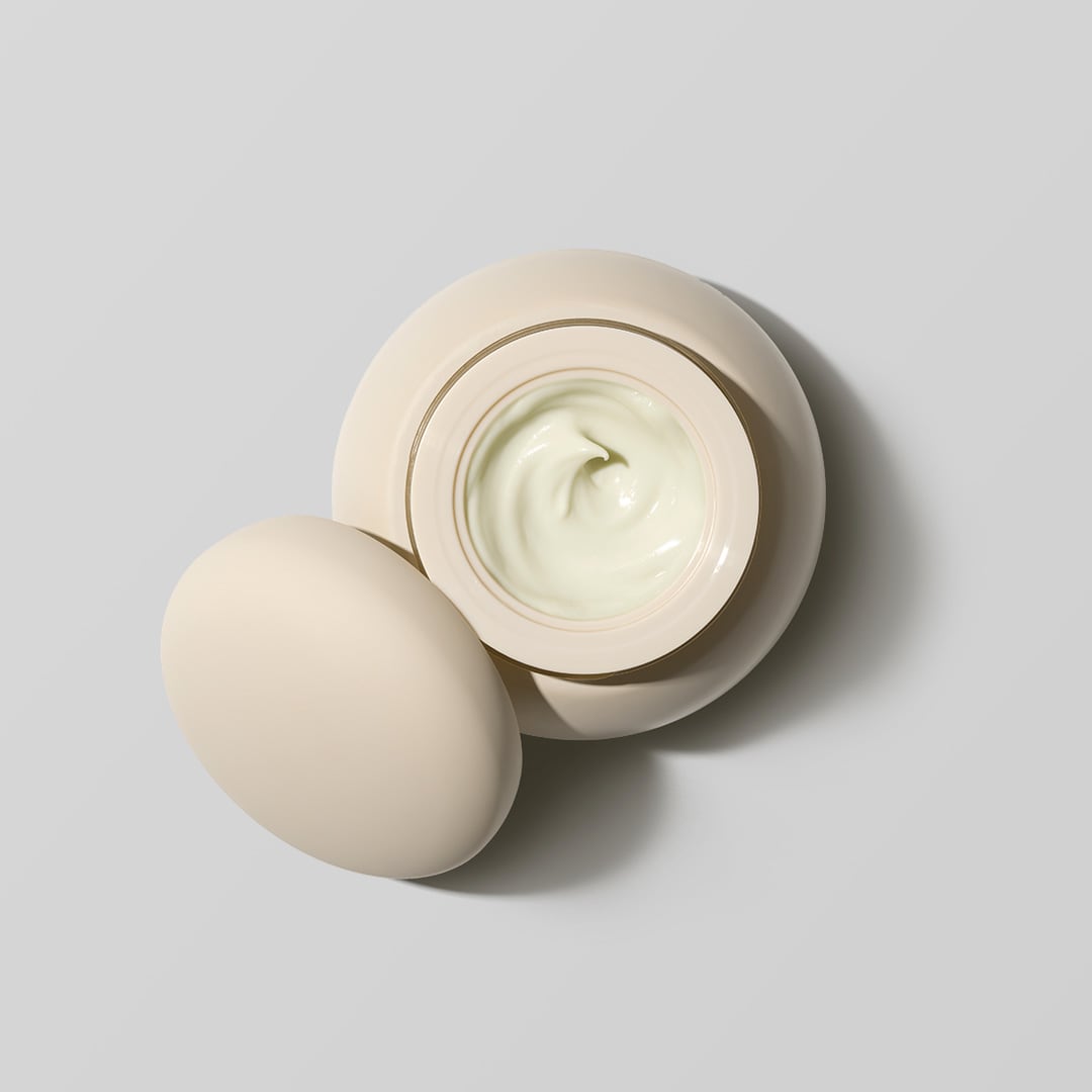 A beige container with its lid removed, showing a swirl of white Cocoon Ceramide Cream hydrating moisturizer inside, rich in ceramides to strengthen your skin barrier by RAAIE.