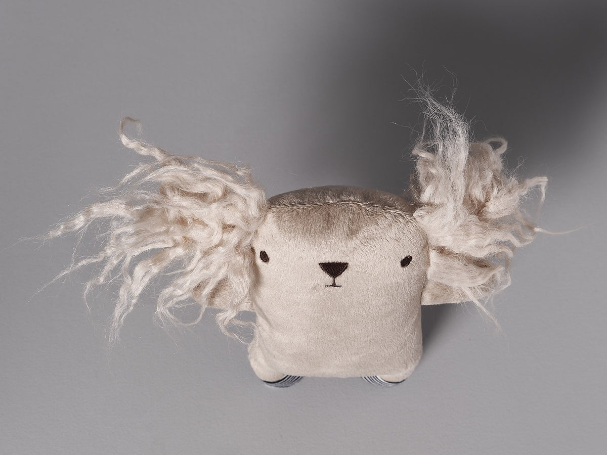 A Raplapla Léo the Dog stuffed animal with long hair on a gray background.