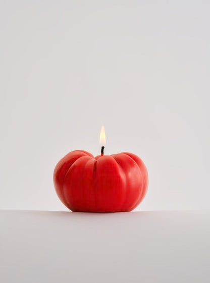 A lifelike Nonna&#39;s Grocer Tomato Candle – Medium sitting on a hand-made white table.