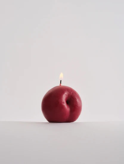 A delightful Nonna&#39;s Grocer plum candle sitting on a white surface.