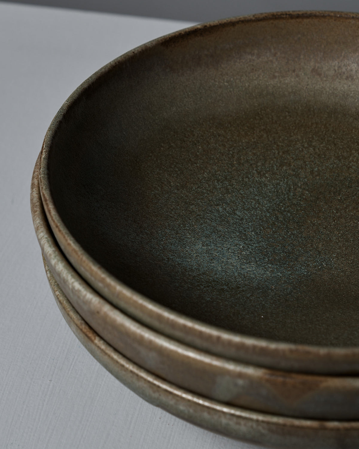 Close-up of three Shallow Serving Bowls – Raw Umber, handmade with a matte, textured finish on a light gray background—crafted by Studio Foon, perfect for serving.