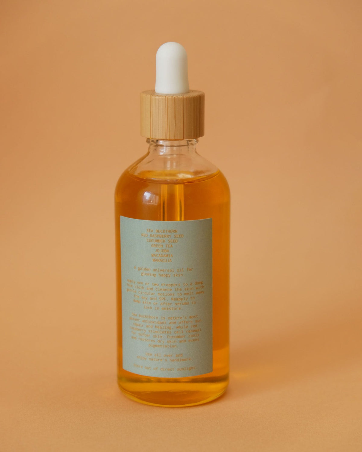 A bottle of Sun Juju Universal Oil – 100𝚐 on a brown background.