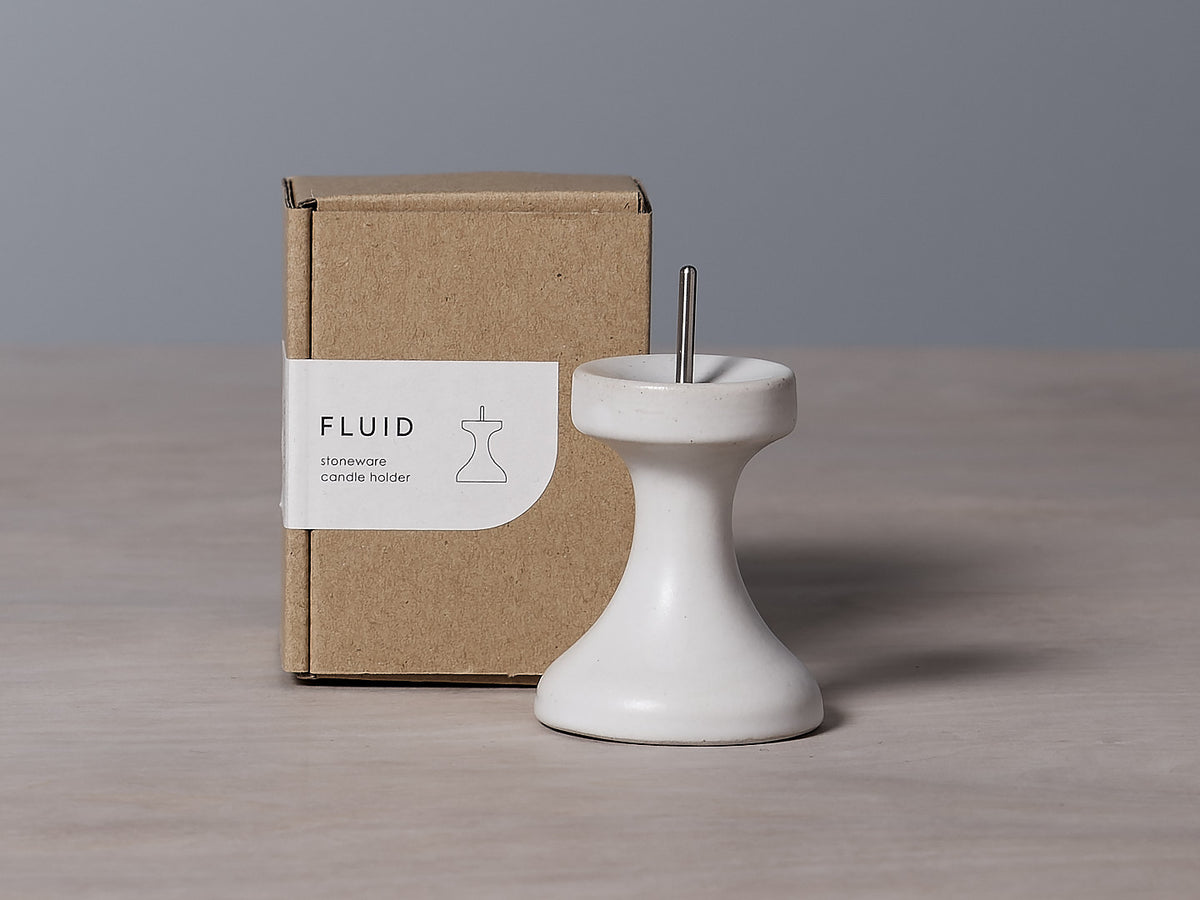 A small FLUID – Stoneware Candle Holder by Takazawa placed on a candle holder.