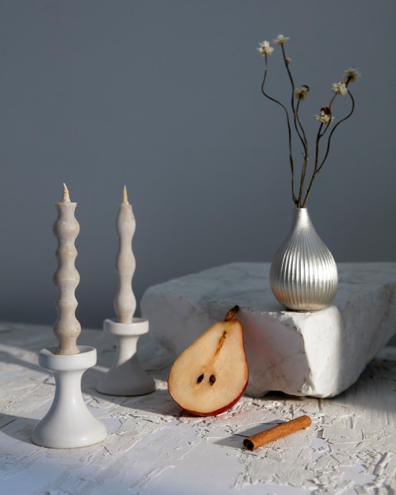 A FLUID – Stoneware Candle Holder by Takazawa with pears and a candle on a table.