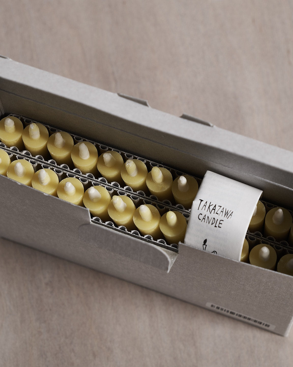 A cluster of yellow Takazawa Nanohana Candles (box of 24), also known as rapeseed flowers, elegantly arranged on a table.