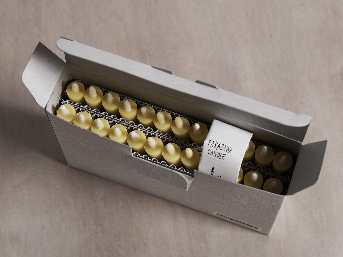 A box of pills adorned with Takazawa Nanohana Candles (box of 24) in a wooden box.