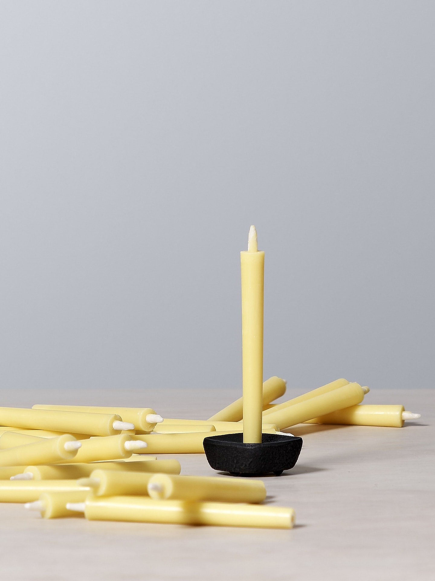 A cluster of yellow Takazawa Nanohana Candles (box of 24), also known as rapeseed flowers, elegantly arranged on a table.