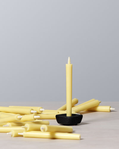 A cluster of yellow Takazawa Nanohana Candles (box of 24), also known as rapeseed flowers, elegantly arranged on a table.