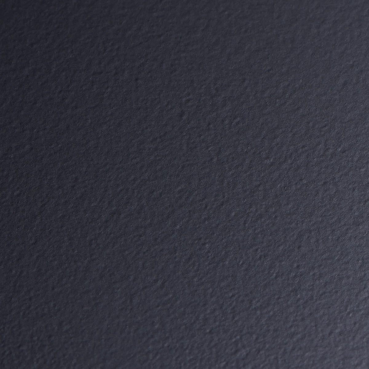 A close-up of the textured black surface of the Camber-Top Toolbox Y-350 by TOYO STEEL reveals a slightly rough finish with subtle shading variations, reminiscent of powder-coated steel.