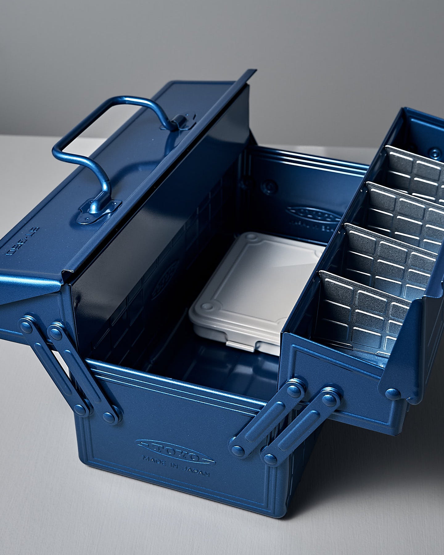 The TOYO STEEL Cantilever Toolbox ST-350 – Blue, featuring powder-coated steel and a checkered pattern, is placed on a white surface against a gray background.
