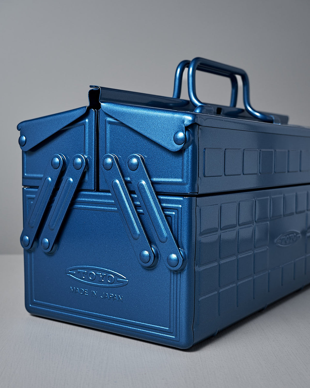 A sleek Cantilever Toolbox ST-350 in blue, featuring a latching mechanism and crafted from durable powder-coated steel, labeled with "TOYO STEEL" and "Made in Japan," rests on a light surface.