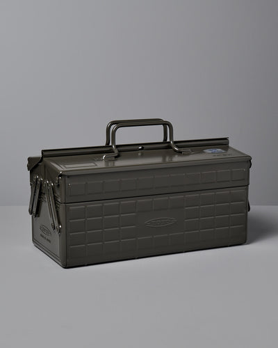 A moss green, powder-coated steel TOYO STEEL Cantilever Toolbox ST-350 with a rectangular shape, clasped lid, and a single handle on top, placed on a gray surface. Made in Osaka.