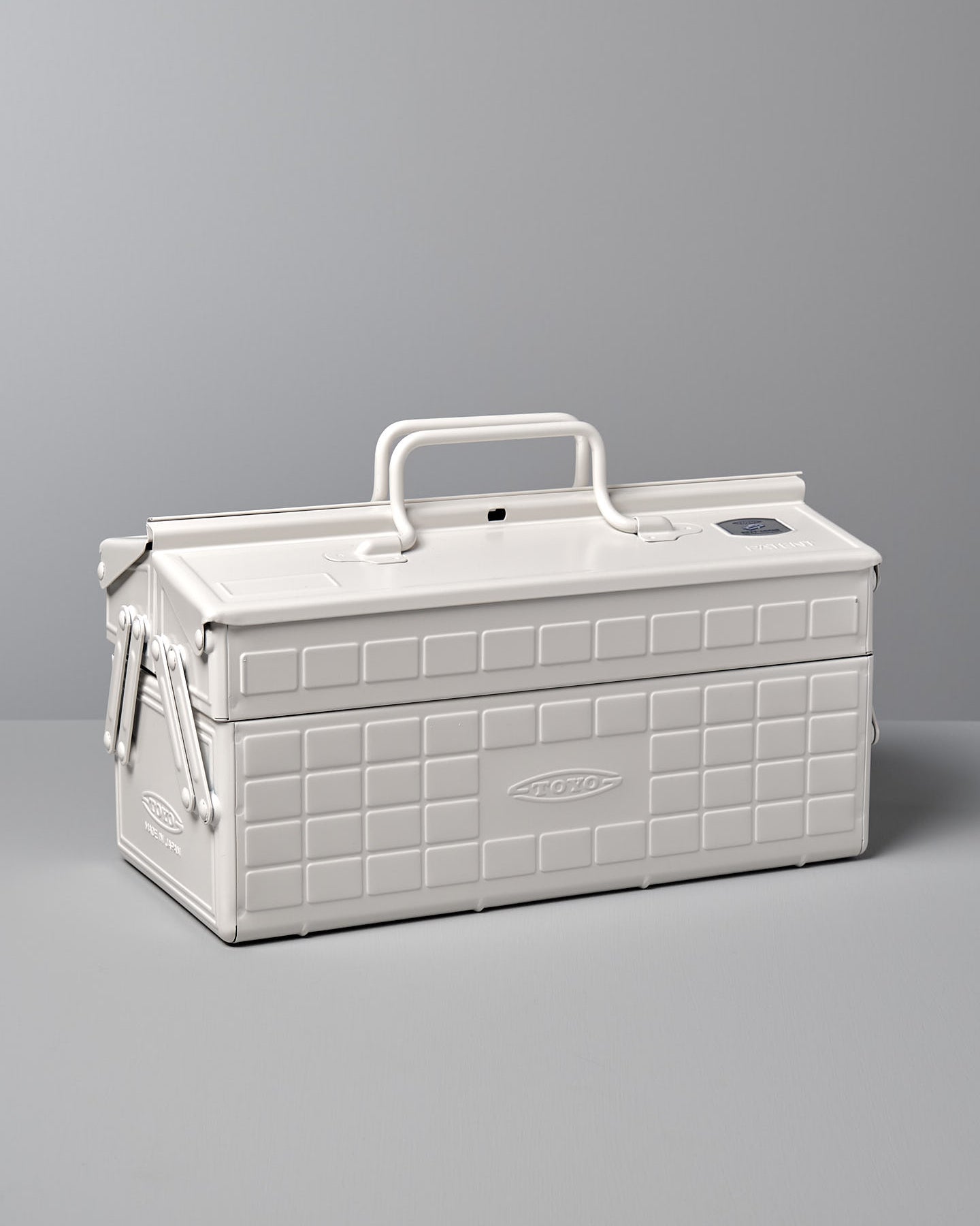 A white, rectangular powder-coated steel toolbox with a handle on top and a latch on the front, placed against a gray background. The Cantilever Toolbox ST-350 – White by TOYO STEEL earned the prestigious Good Design Award 2009.