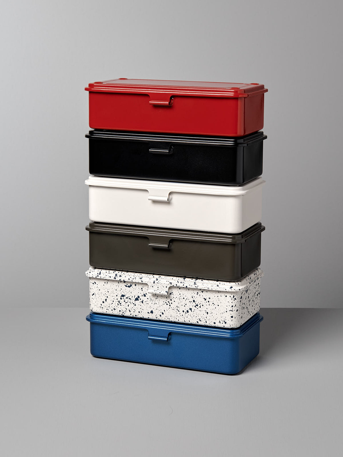 A stack of six versatile, stackable Mini Steel Toolbox T-190 – White by TOYO STEEL in various colors and patterns, including red, black, white, dark green, speckled white, and blue, arranged against a plain gray background.