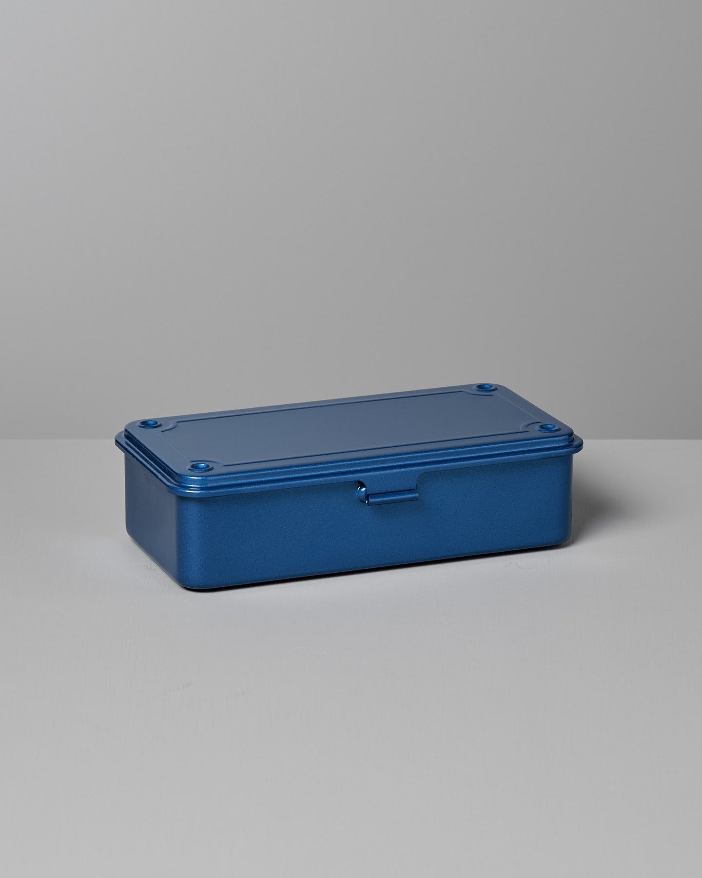 A Mini Steel Toolbox T-190 – Blue by TOYO STEEL with a hinged lid sits on a gray surface against a gray background, offering a versatile storage solution.