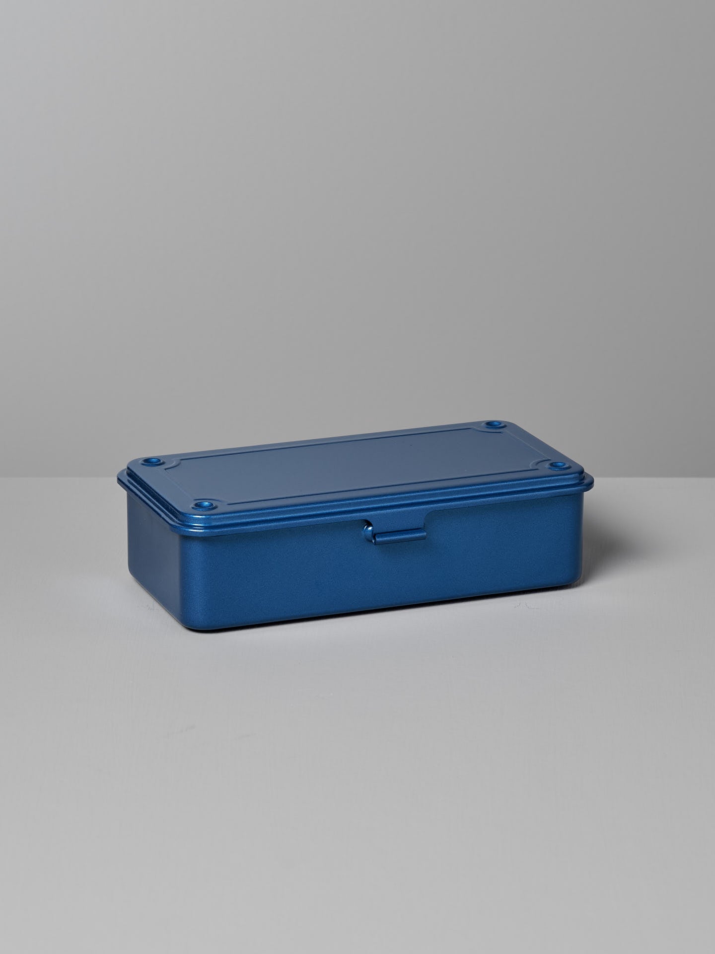 A Mini Steel Toolbox T-190 – Blue by TOYO STEEL with a hinged lid sits on a gray surface against a gray background, offering a versatile storage solution.