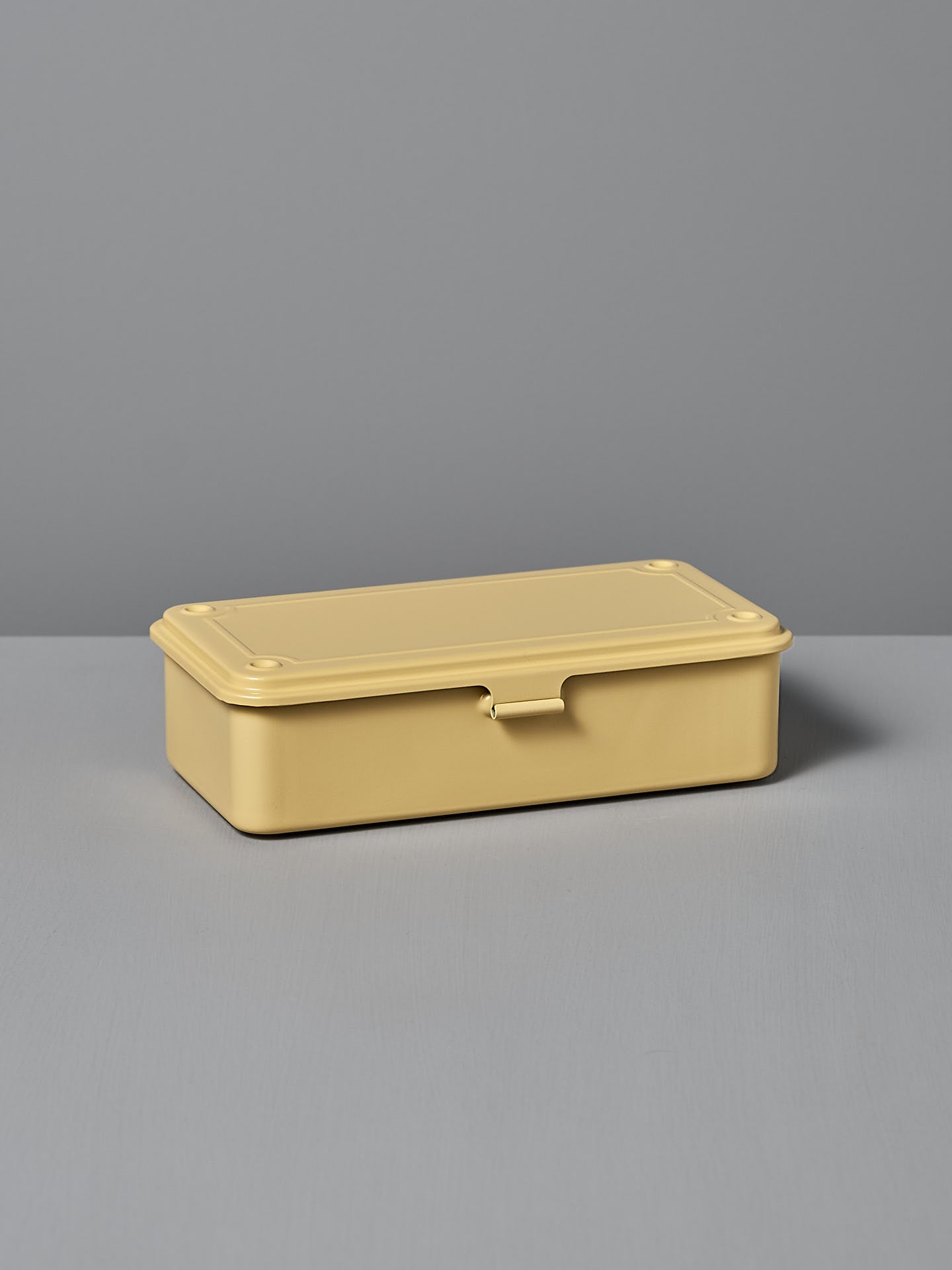 A rectangular Mini Steel Toolbox T-190 in Italian Yellow from TOYO STEEL, crafted from powder-coated steel, rests on a flat surface against a gray background, showcasing its versatile design and durability.