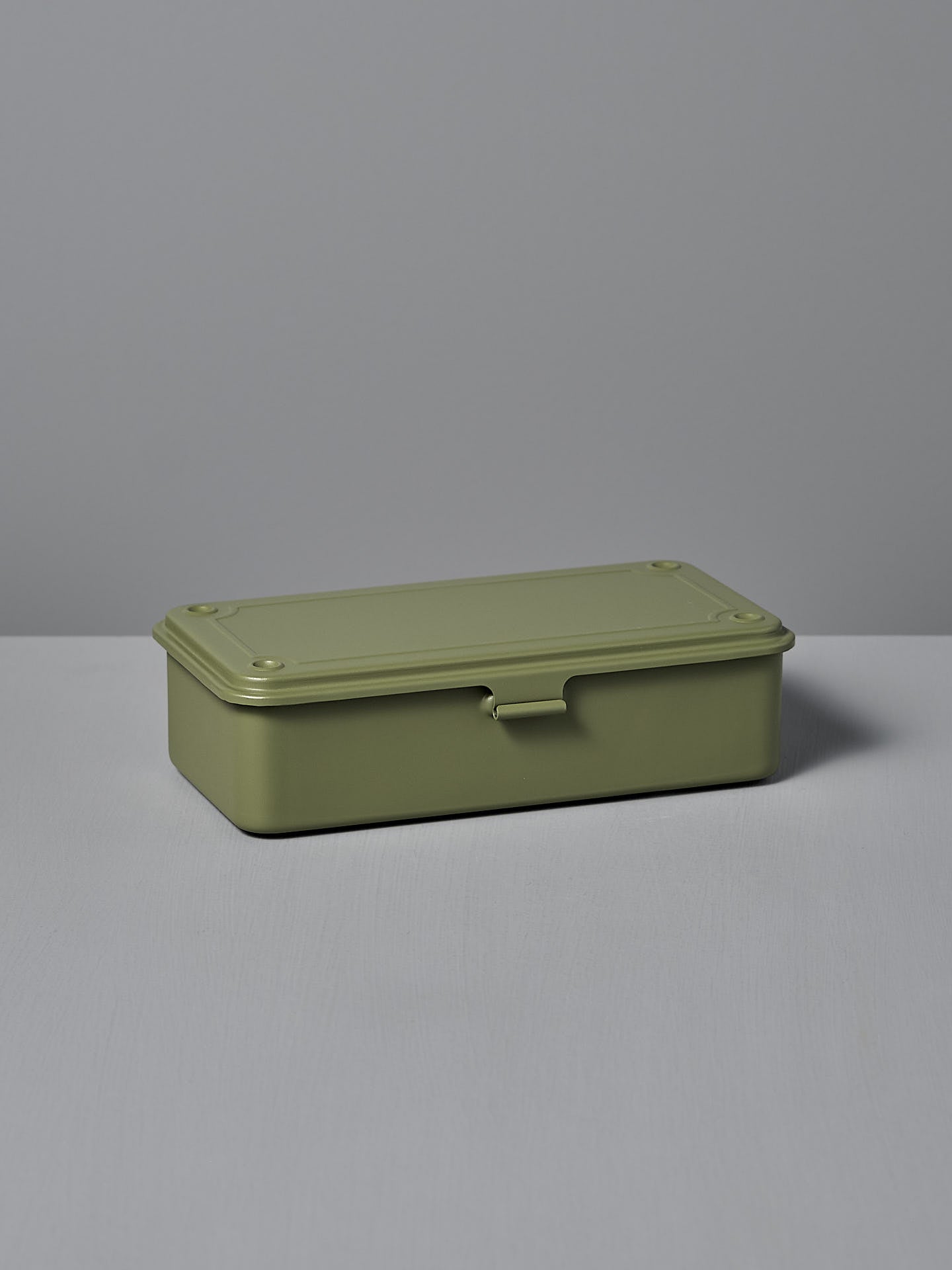The TOYO STEEL Mini Steel Toolbox T-190 in Japanese Tea Green, a closed rectangular box made from powder-coated steel, sits on a light gray surface, offering a versatile storage solution.