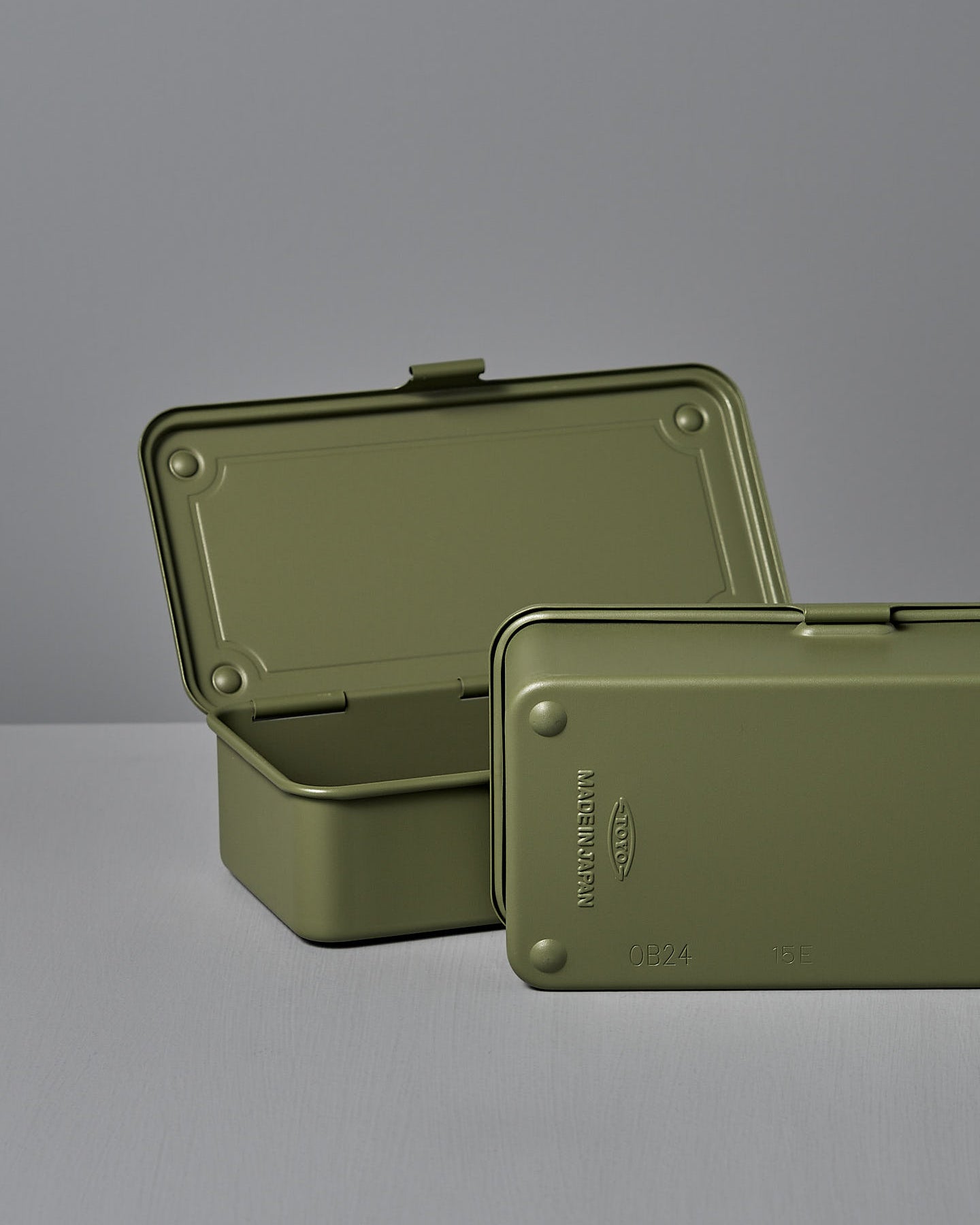 The TOYO STEEL Mini Steel Toolbox T-190 in Japanese Tea Green, a closed rectangular box made from powder-coated steel, sits on a light gray surface, offering a versatile storage solution.