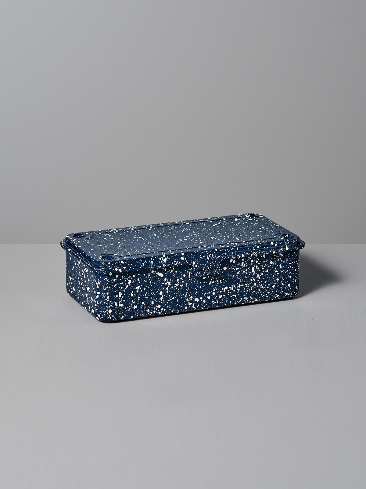 The Mini Steel Toolbox T-190 – Japanese Indigo by TOYO STEEL, a rectangular steel storage box with a speckled blue and white finish and matching lid, rests on a gray surface, offering a versatile design that enhances any space.