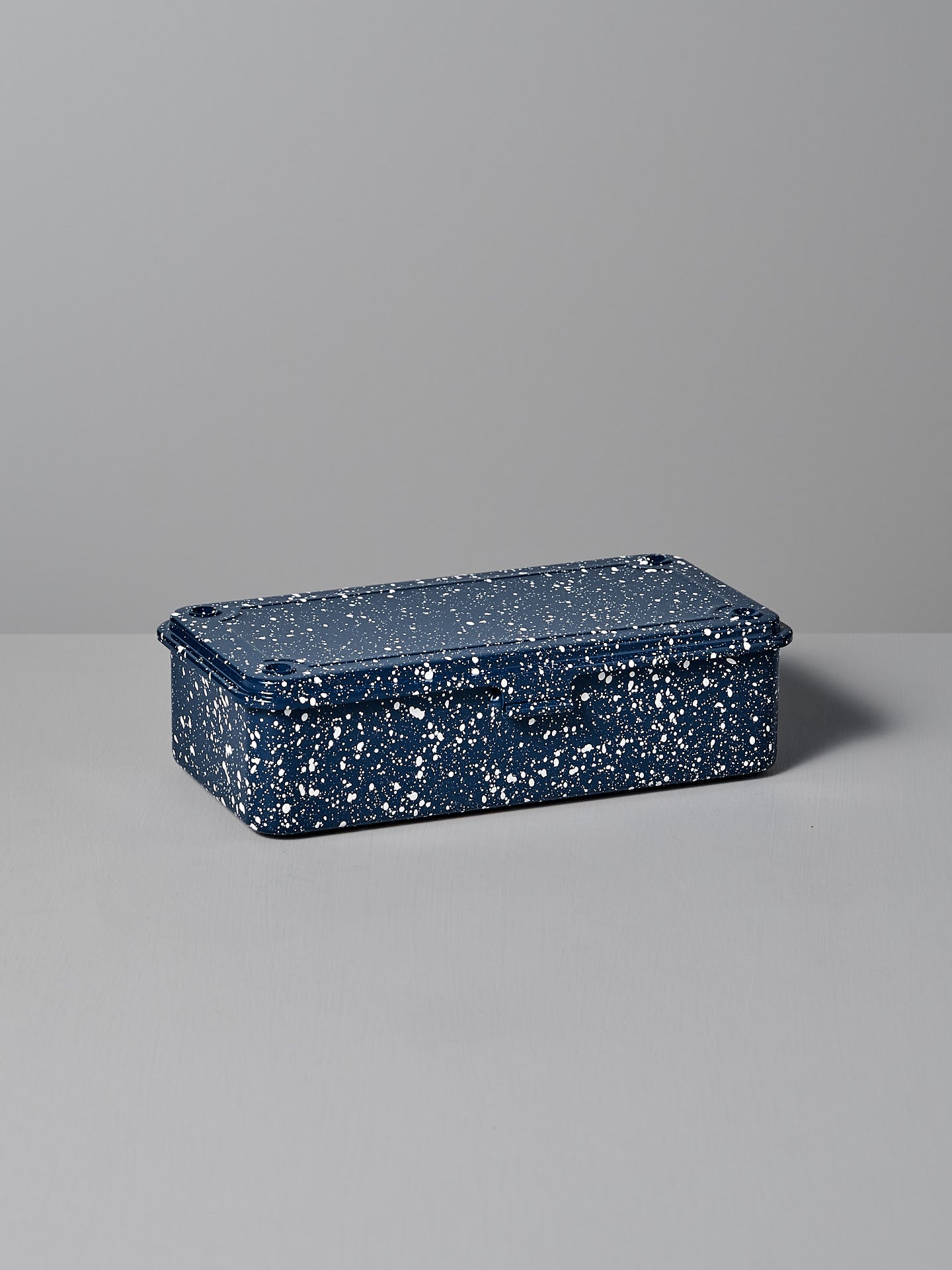 The Mini Steel Toolbox T-190 – Japanese Indigo by TOYO STEEL, a rectangular steel storage box with a speckled blue and white finish and matching lid, rests on a gray surface, offering a versatile design that enhances any space.