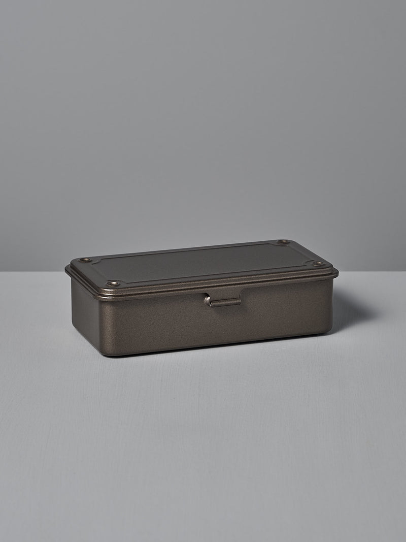 The Mini Steel Toolbox T-190 – Titanium by TOYO STEEL, a rectangular powder-coated tin box with a dark finish, hinged lid, and rivet details, is positioned on a flat surface against a plain background.