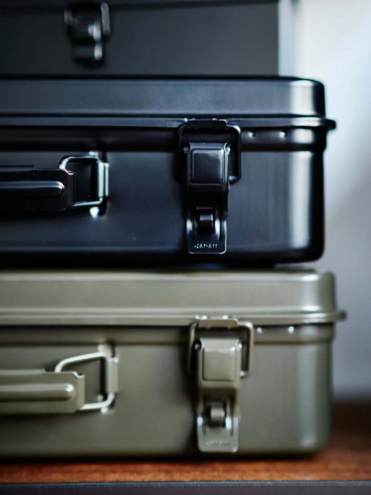 A moss green Trunk-style Toolbox T-360 with sturdy latches and handles sits on a wooden surface.