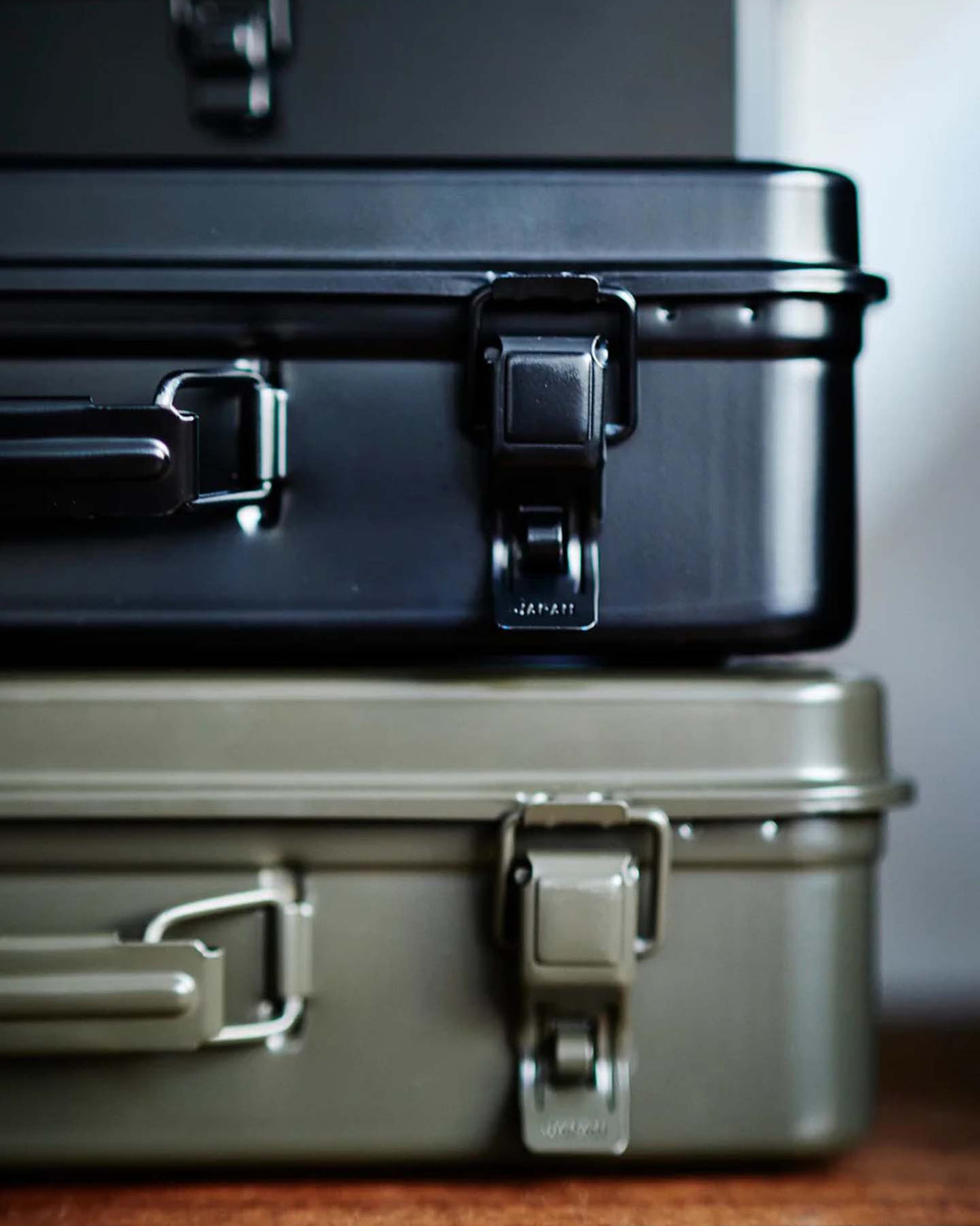 A moss green Trunk-style Toolbox T-360 with sturdy latches and handles sits on a wooden surface.