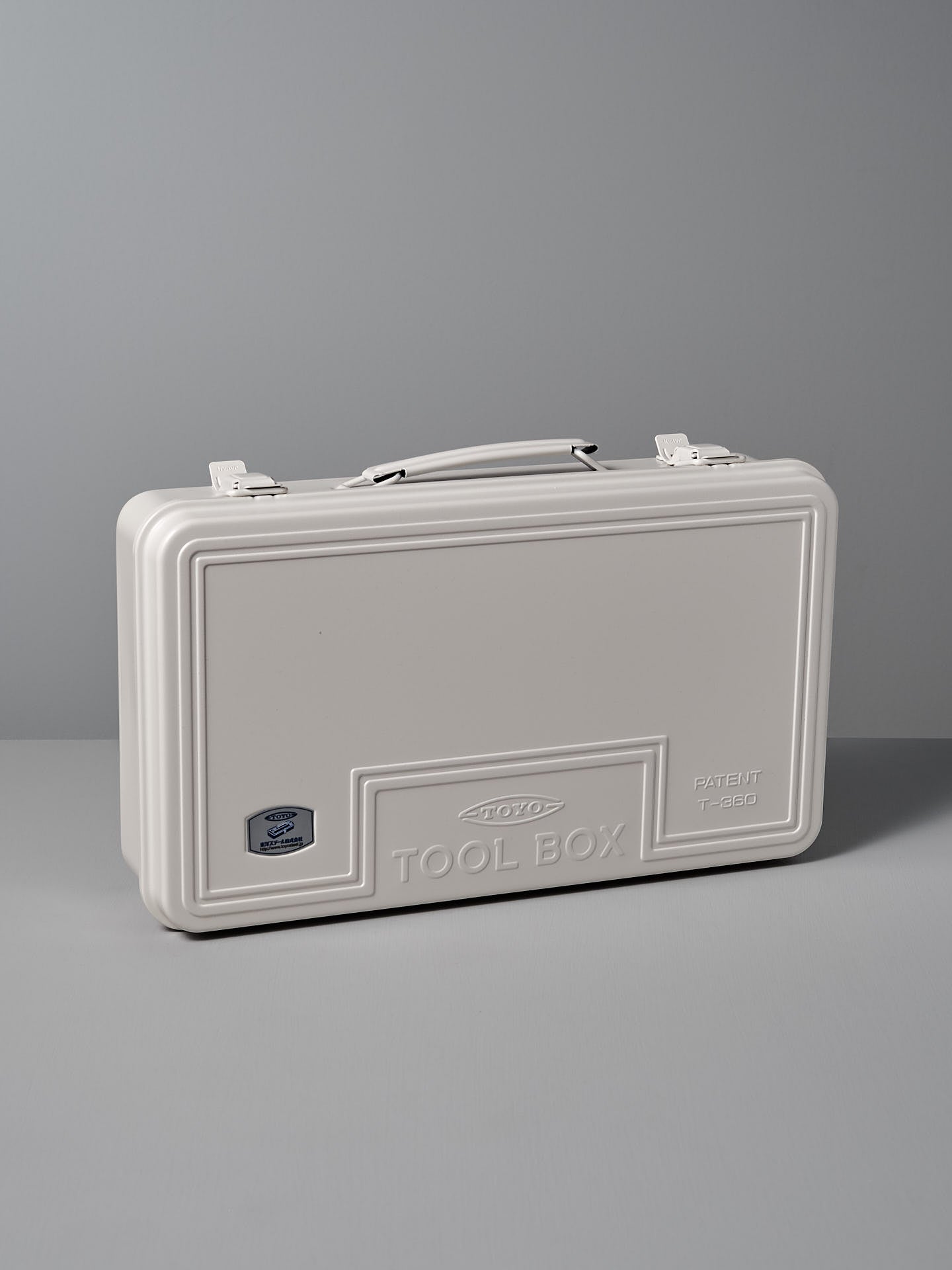 The Trunk-style Toolbox T-360 – White by TOYO STEEL, made from powder-coated steel and featuring an embossed "TOOL BOX" with a patent number, offers an excellent storage solution set against a gray background.