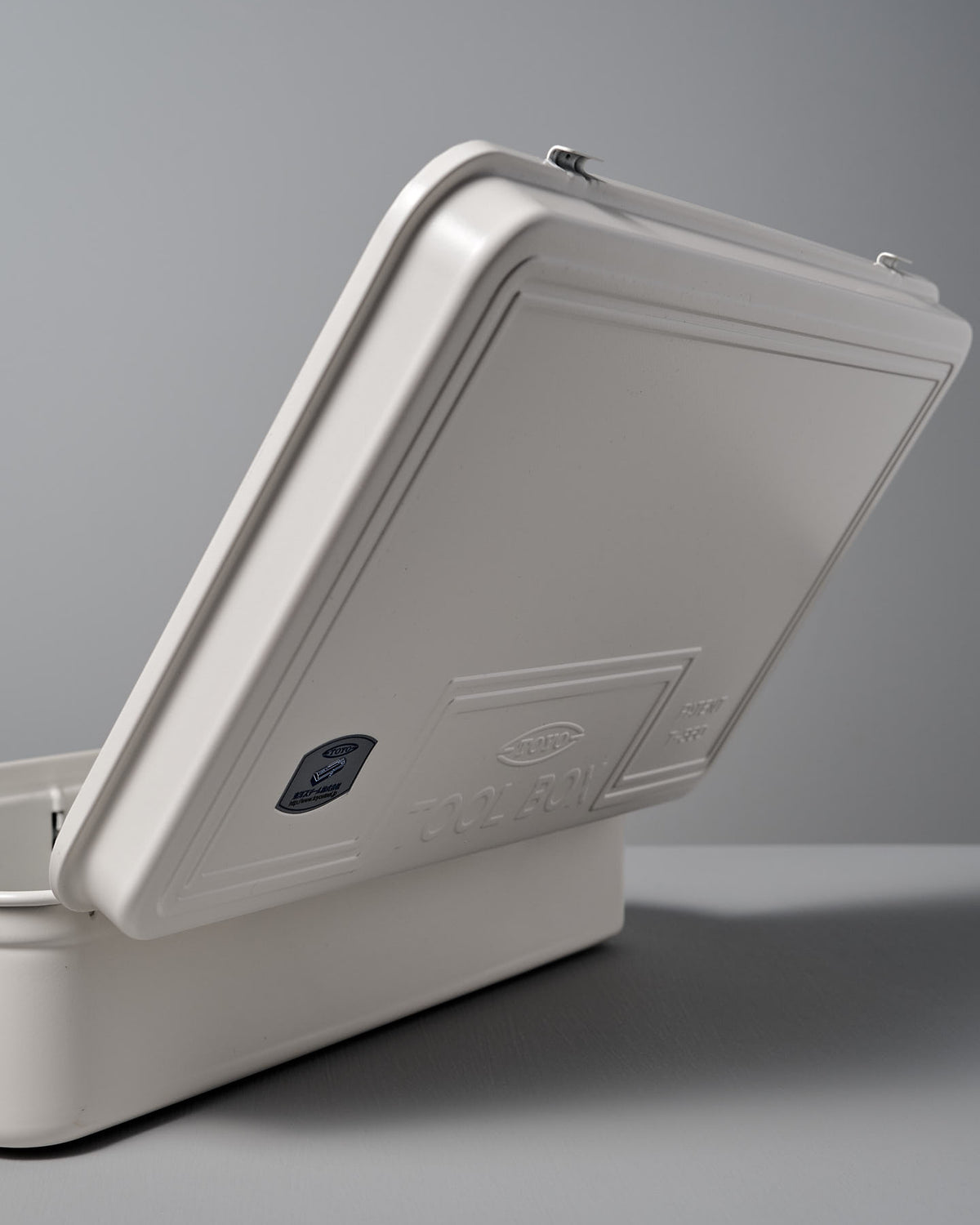 A unique storage solution, the Trunk-style Toolbox T-360 in white by TOYO STEEL is crafted from powder-coated steel with an open lid, resting on a gray surface and showcasing a vintage style.